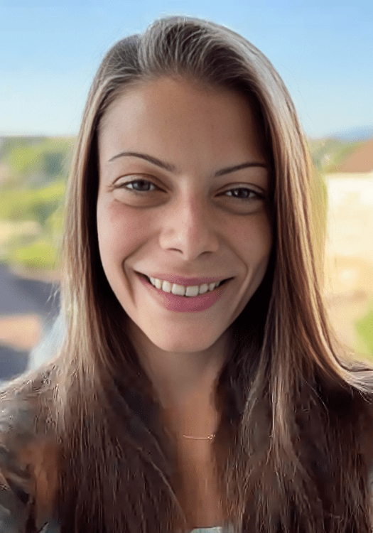 Smiling person with long hair outdoors.